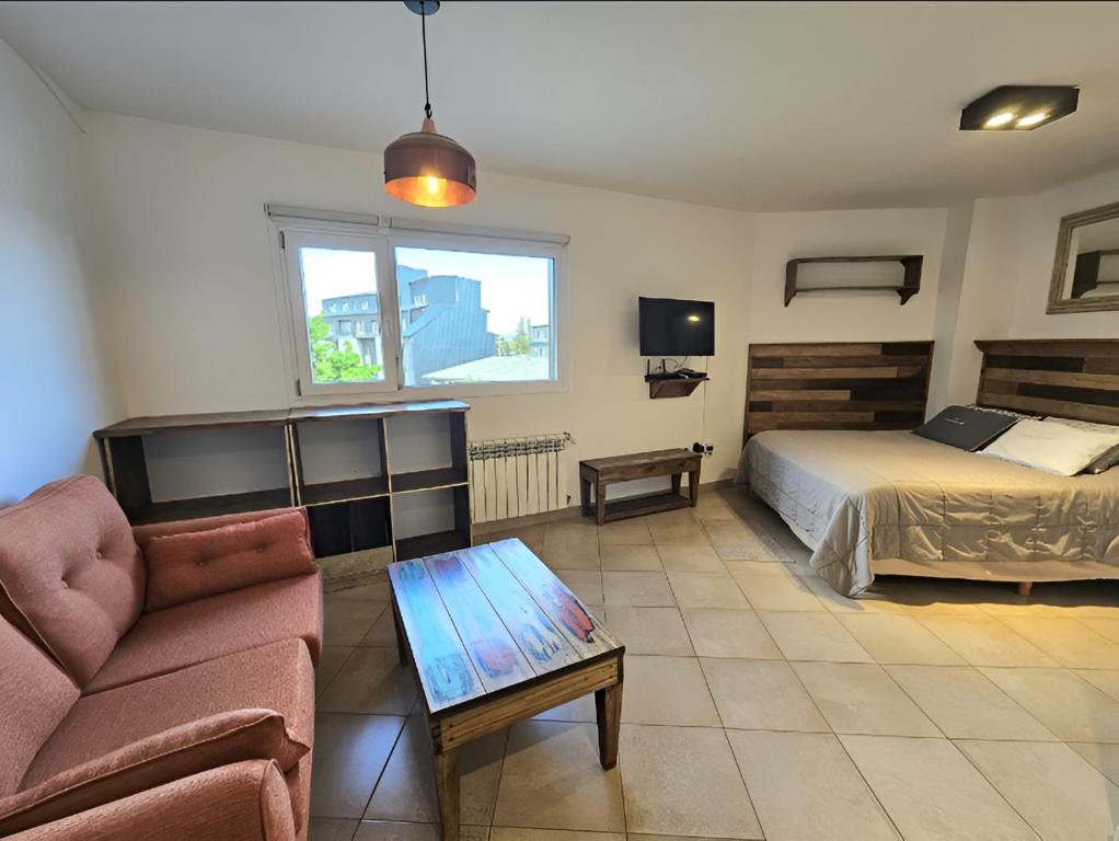 a bedroom with a bed and a couch and a table at LOS COCOS Divino monoambiente de diseño propio in San Carlos de Bariloche