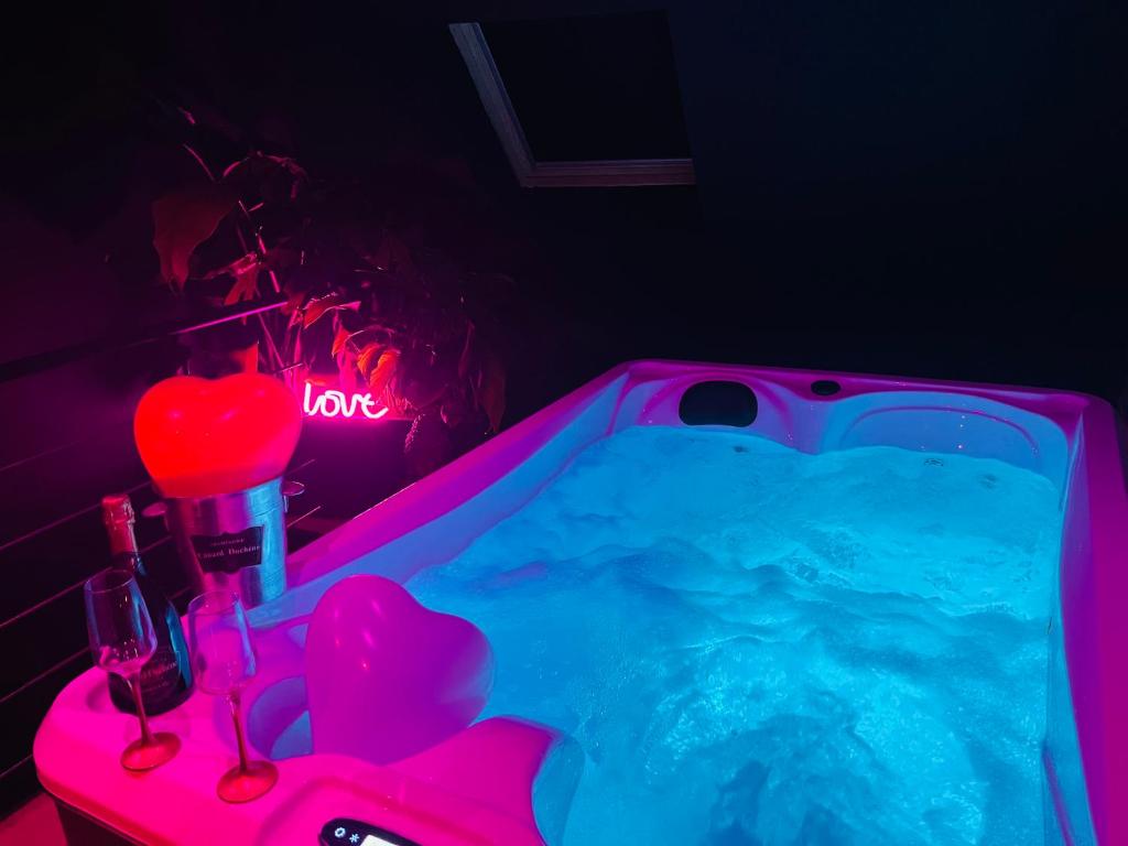 a bathroom with a tub with a neon light at Chambre Noire in Solre-le-Château