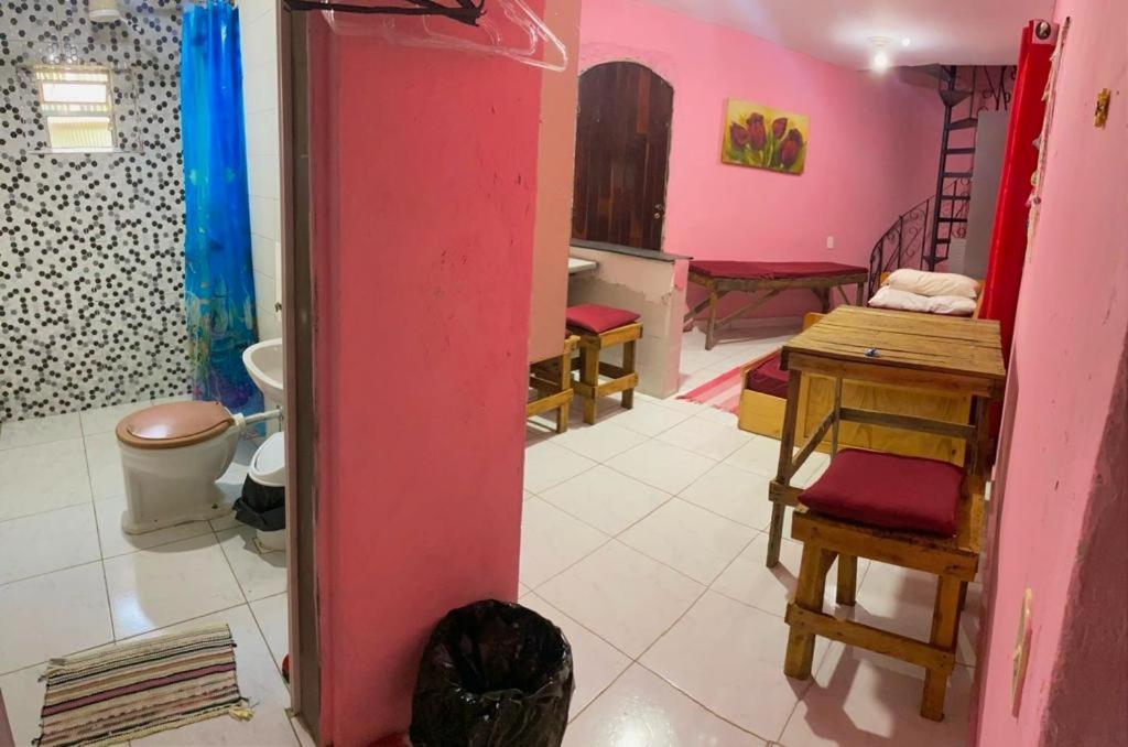 a bathroom with pink walls and a table and a toilet at Casa Jambo Hostel Para Mulheres in Guarujá
