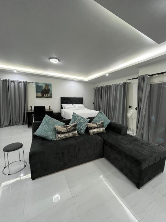 a living room with a black couch in front of a bed at Onelove Homes in Lusaka