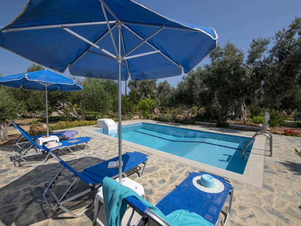 a pool with blue umbrellas and chairs and a swimming pool at Nice villa on small beautiful complex of 3 villas communal pool NW coast in Pangalochori