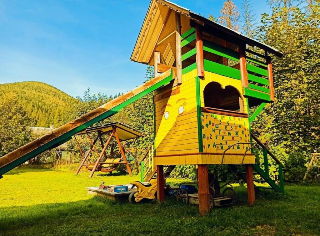 a large wooden play house with a slide at Max hoMe in Tatariv