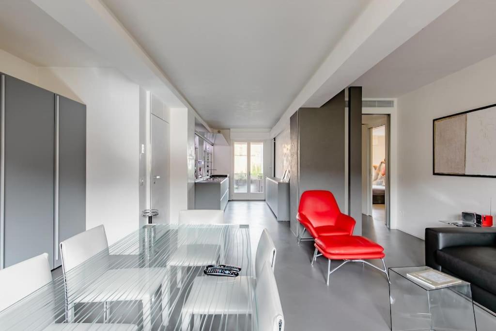 a living room with a glass table and a red chair at luxury apartment in Pesaro
