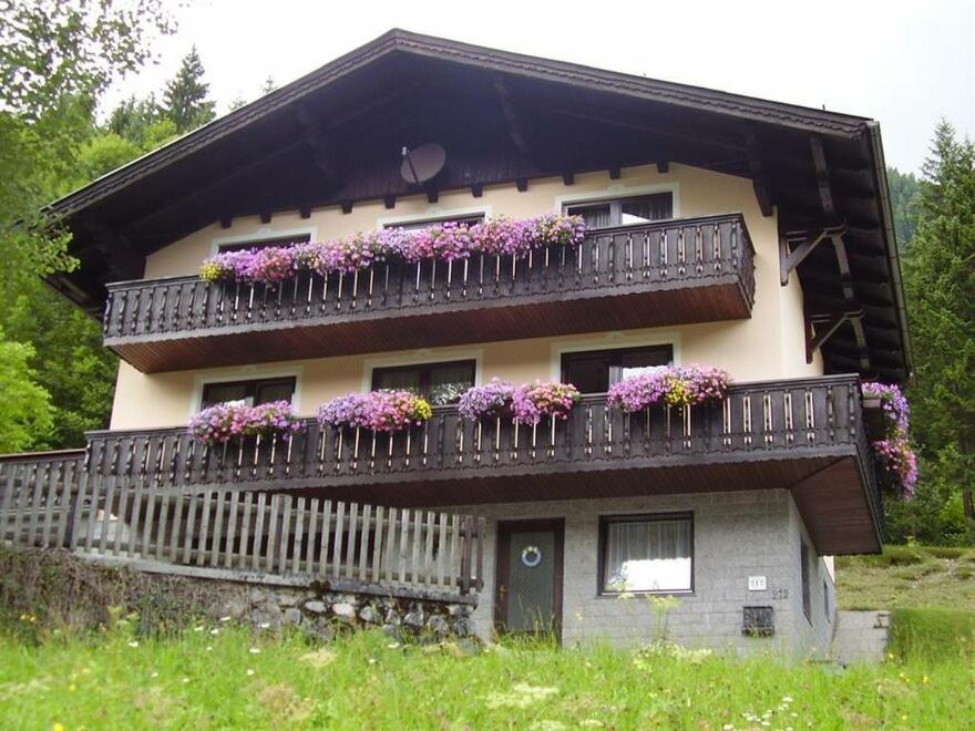 une maison avec des boîtes de fleurs sur le balcon dans l'établissement Haus Bergheim, à Ramsau am Dachstein