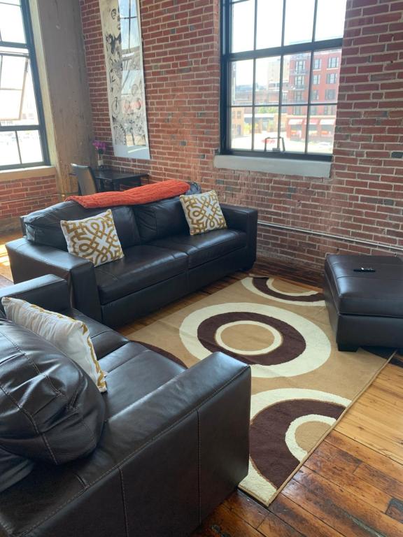 a living room with couches and a brick wall at Luxe Art Gallery in Saint Louis