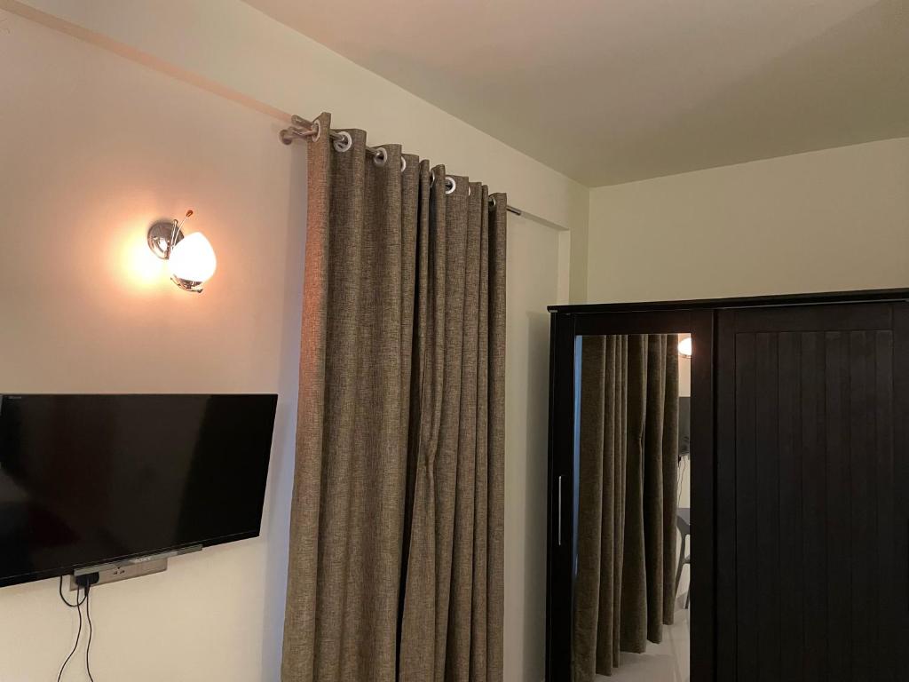 um quarto com uma televisão de ecrã plano e cortinas em Oren em Maamigili