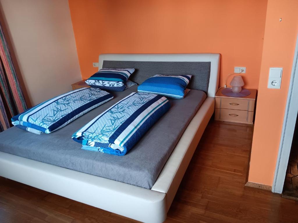 Bett mit blauen Kissen auf einem Zimmer in der Unterkunft Ländlezimmer in Rankweil