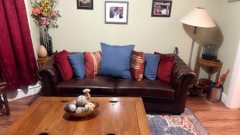 una sala de estar con un sofá de cuero marrón con almohadas coloridas en Genevieve’s comfort pad, en Jersey City