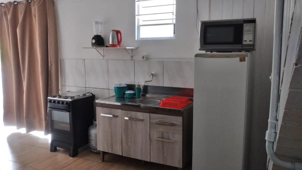 a small kitchen with a sink and a refrigerator at Kitnet Avenida in Imbituba