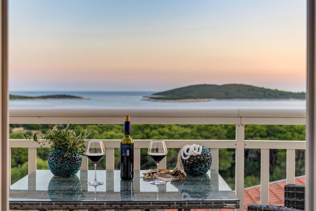 a table with two glasses of wine on a balcony at B&B Paradiso - Pakleni Islands Hvar in Hvar