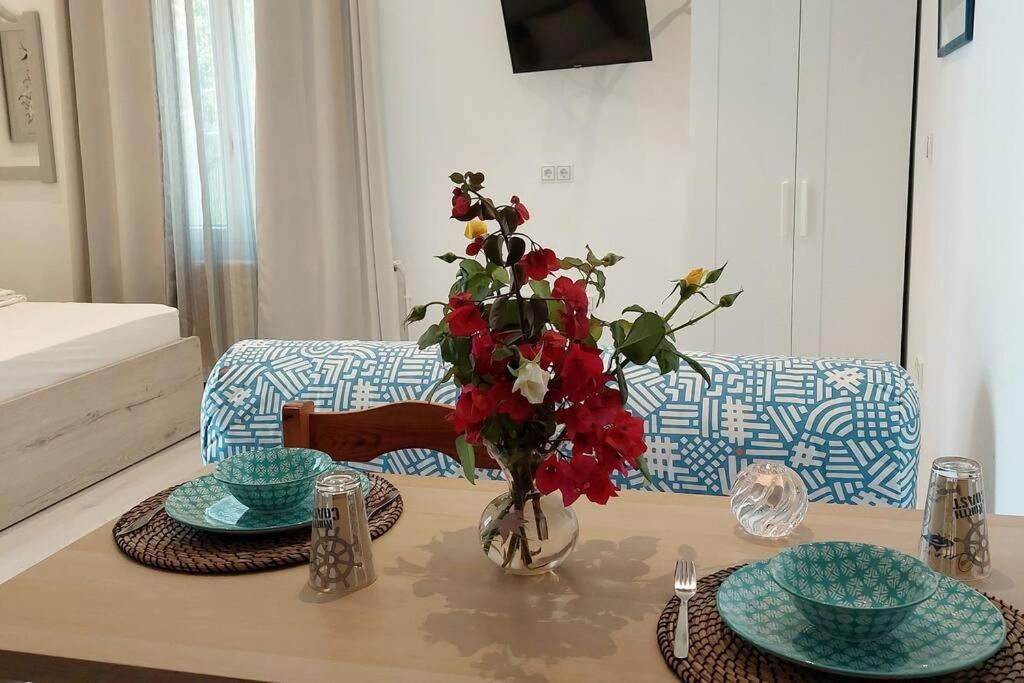 a table with two plates and a vase with red flowers at Seaside cushy studio in Kampos Paros