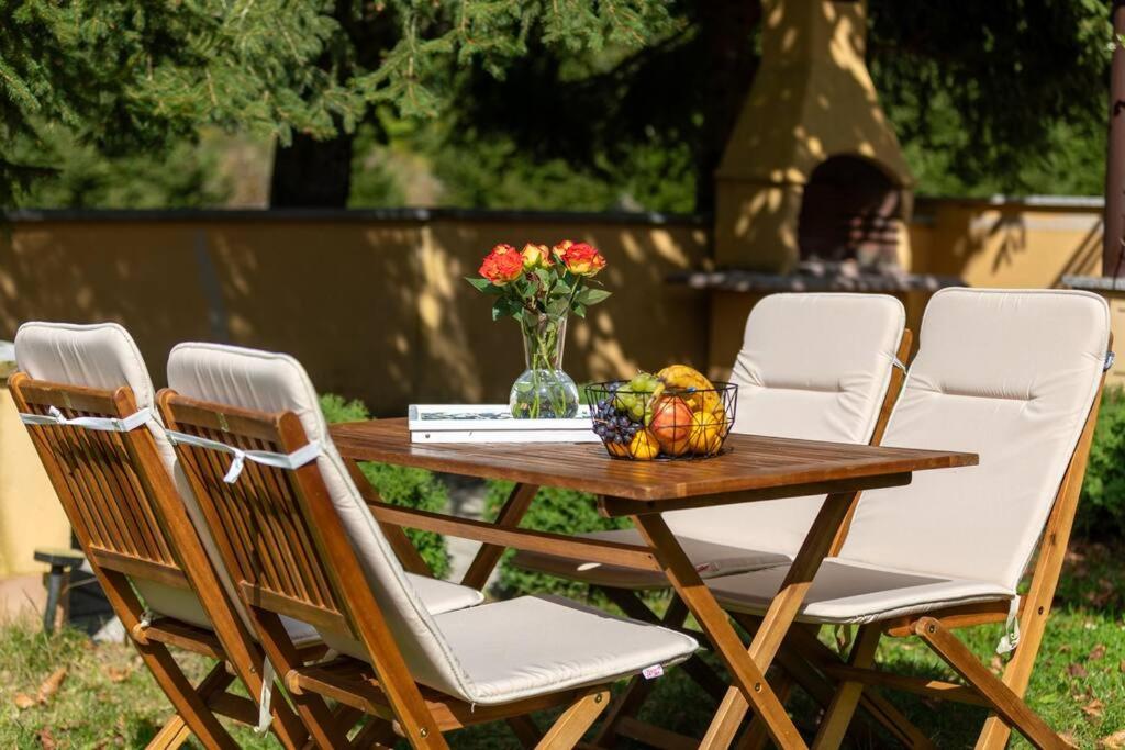 een houten tafel met vier stoelen en een vaas met bloemen bij Apartmani Rumora Gorski kotar in Tuk Vojni