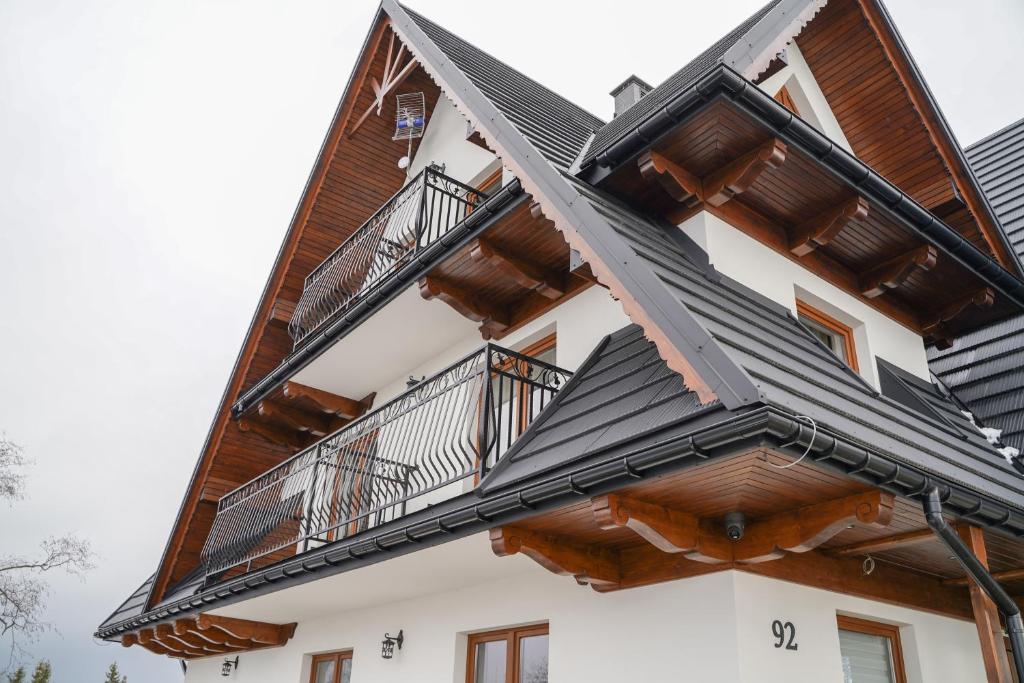 a house with a wooden roof and balconies on it at Goralsko Manufaktura in Bukowina Tatrzańska