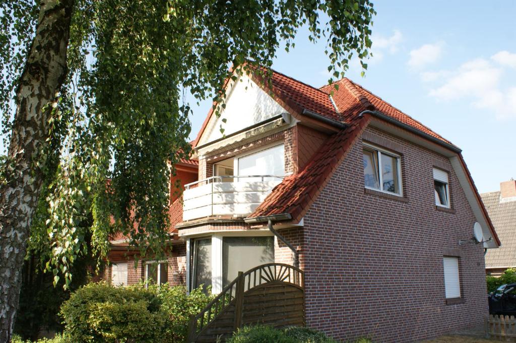 a red brick house with a large tree at Ferienwohnung Fehn in Rhauderfehn