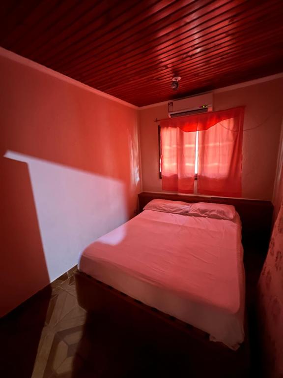 a small bedroom with a bed with a red window at Apart Belén in Puerto Iguazú