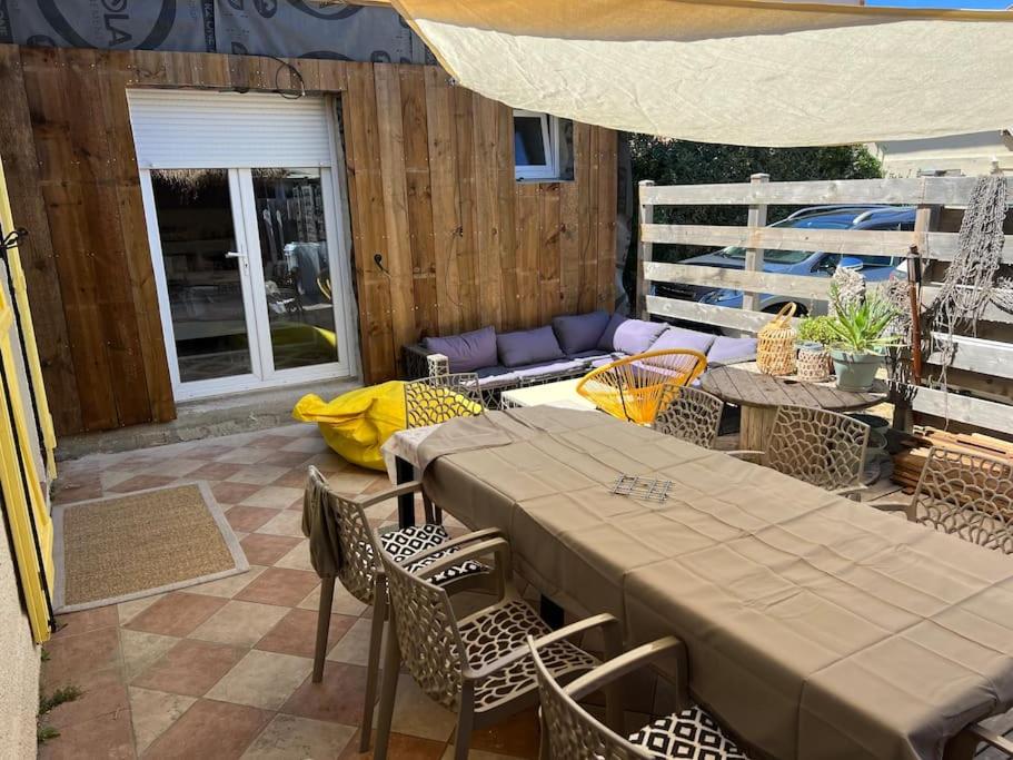 un patio avec une table, des chaises et un canapé dans l'établissement JoePolly surf House, à Lacanau