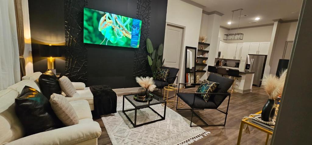 a living room with a couch and a tv on a wall at Luxury 2br Apartment (Buckhead) in Atlanta