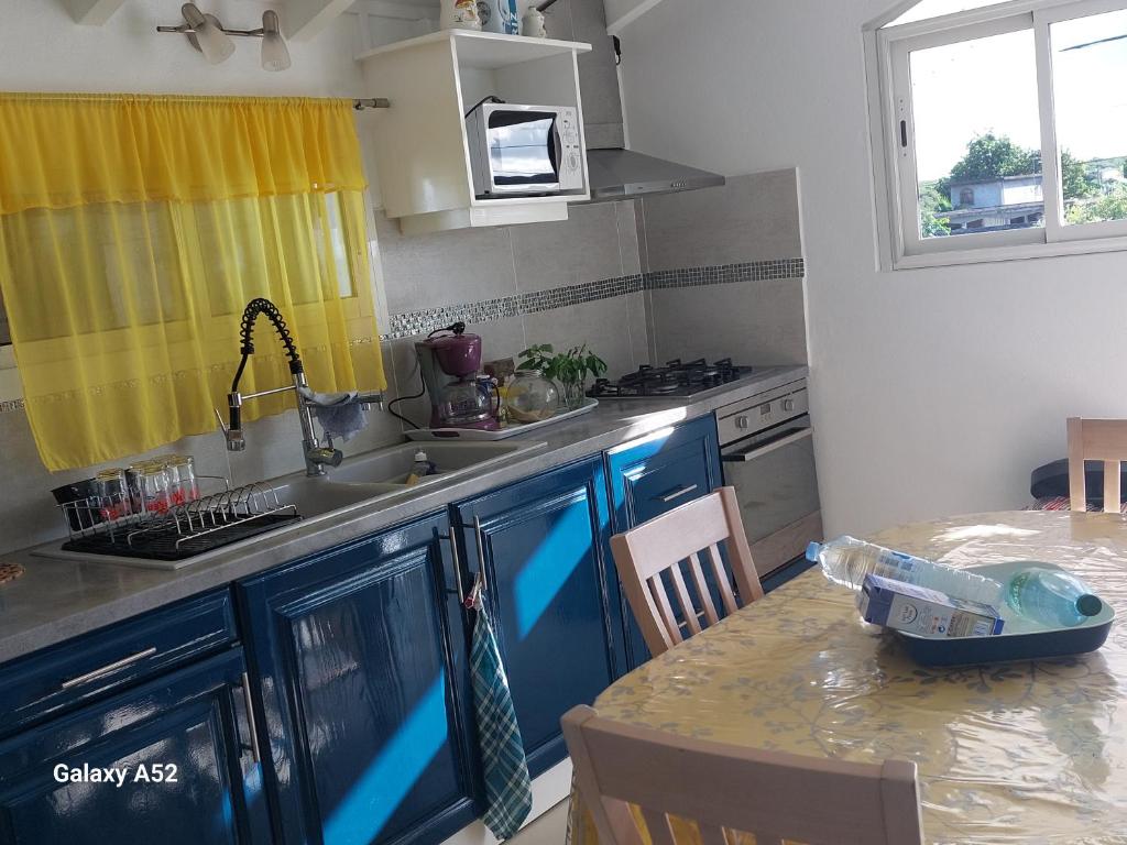Anse-Bertrand的住宿－Haut de villa agréable et paisible climatise, wifi，厨房配有蓝色和黄色的橱柜和桌子