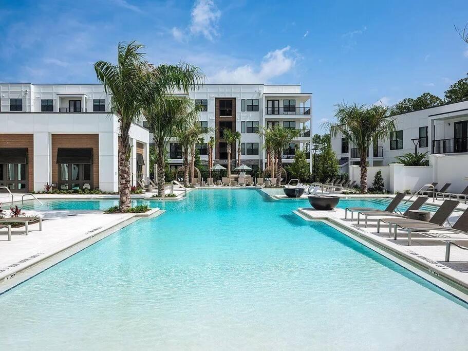 a large swimming pool with chairs and a building at 5 STAR Upscale King Suite 1 Min to Mayo Clinic in Jacksonville