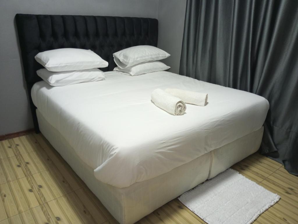 een bed met witte lakens en kussens erop bij Ramachi apartments in Livingstone