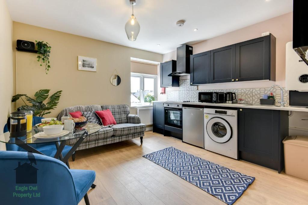 a kitchen and living room with a couch and a table at 1 bed flat for two close to train station with private parking by Eagle Owl Property in Worthing