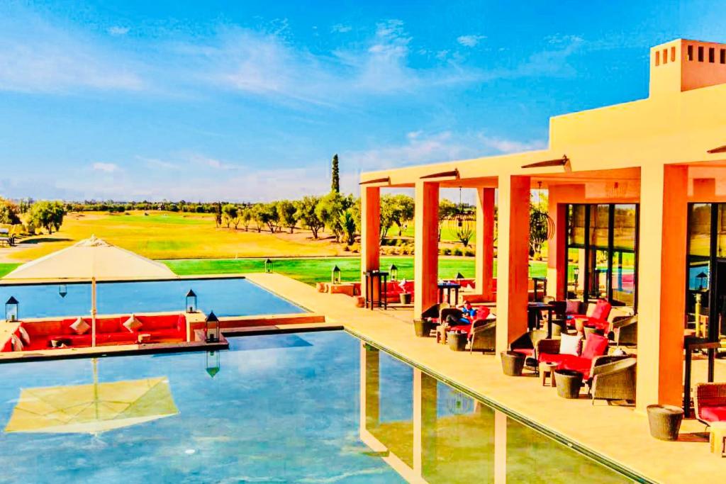 um resort com uma piscina com cadeiras e mesas em Villa Marrakech em Marraquexe