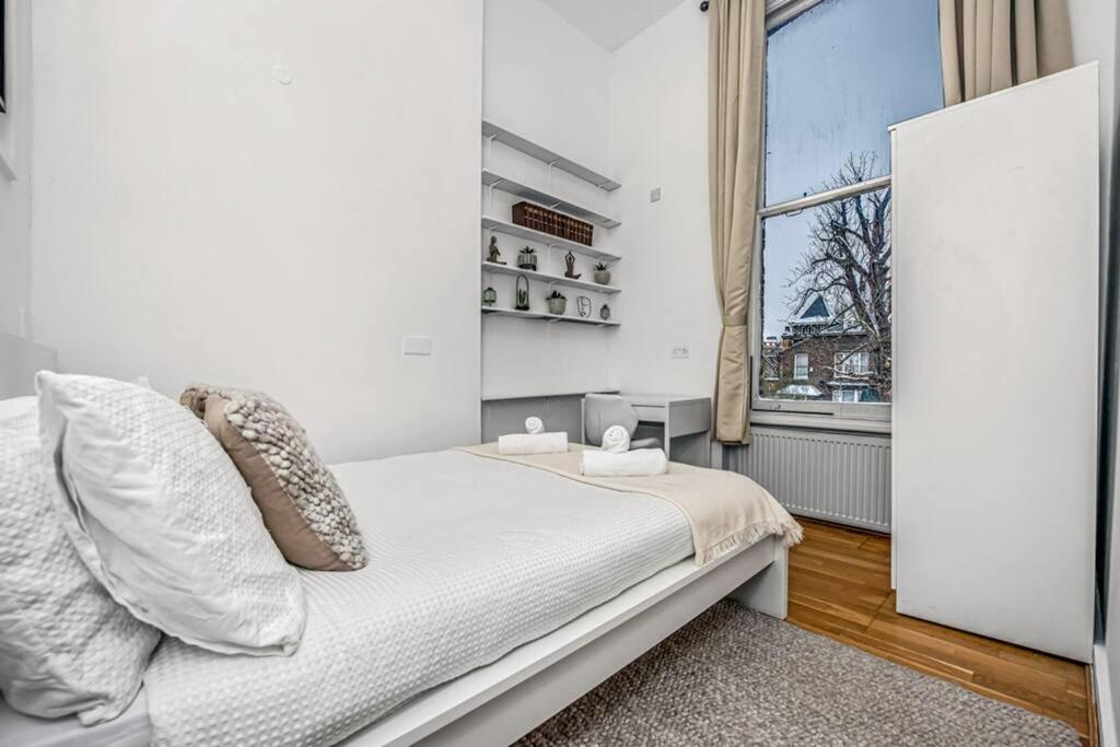 a white bedroom with a bed and a window at Deluxe flat on Kentish Town in London