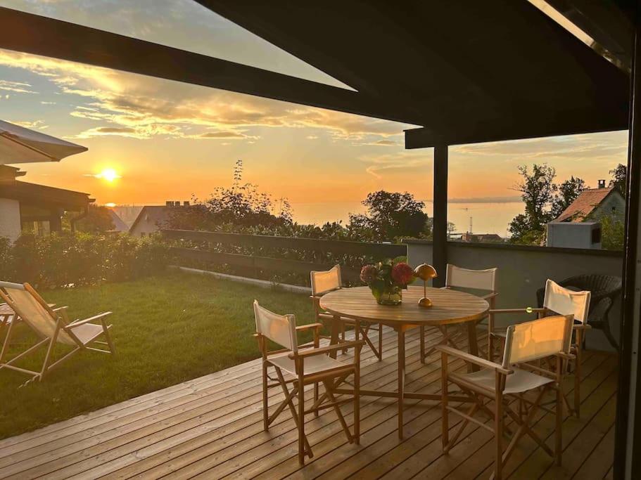 uma mesa e cadeiras num deque com o pôr-do-sol em Haus A Ankommen-Abschalten-Auftanken em Bregenz