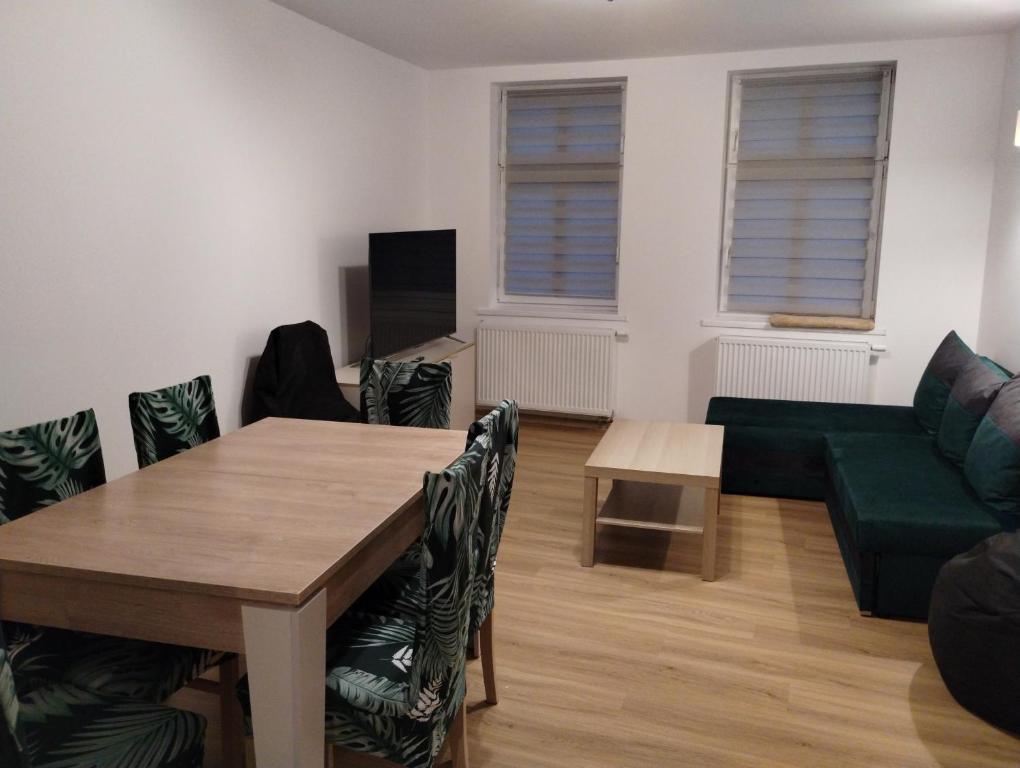 uma sala de estar com uma mesa e um sofá verde em Apartament Tereska em Duszniki Zdrój