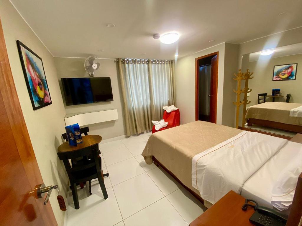 Hotel Cisneros 700 في ليما: غرفة نوم بسرير ومكتب وتلفزيون