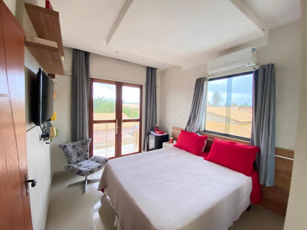 um quarto com uma cama com almofadas vermelhas e uma janela em Casa Vitória em Estância