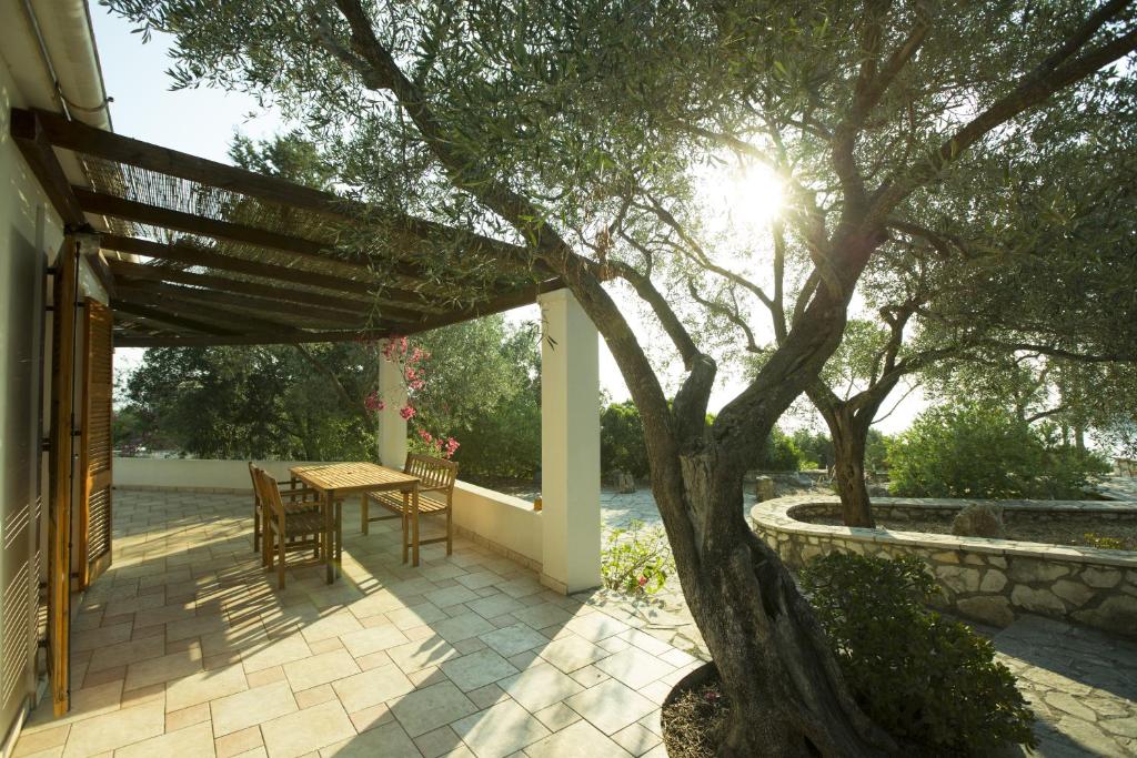 a patio with a table and a tree at Nereidi Villas in Porto Ozias