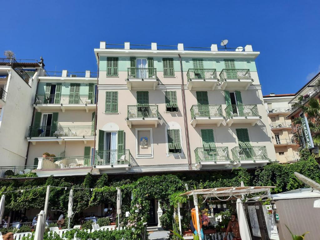 un gran edificio blanco con balcones y árboles en Hotel Eden Alaxi Hotels, en Alassio