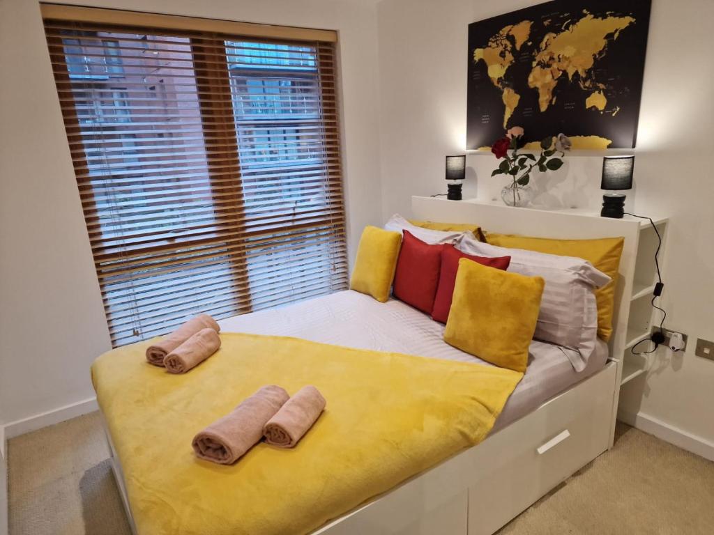 Luxury Modern Apartment Stay في شيفيلد: غرفة نوم بسرير ومخدات صفراء وحمراء