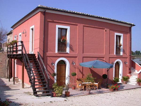 un edificio rosso con tavolo e ombrellone di Country House Agriturismo Ciuccunit a Bucchianico