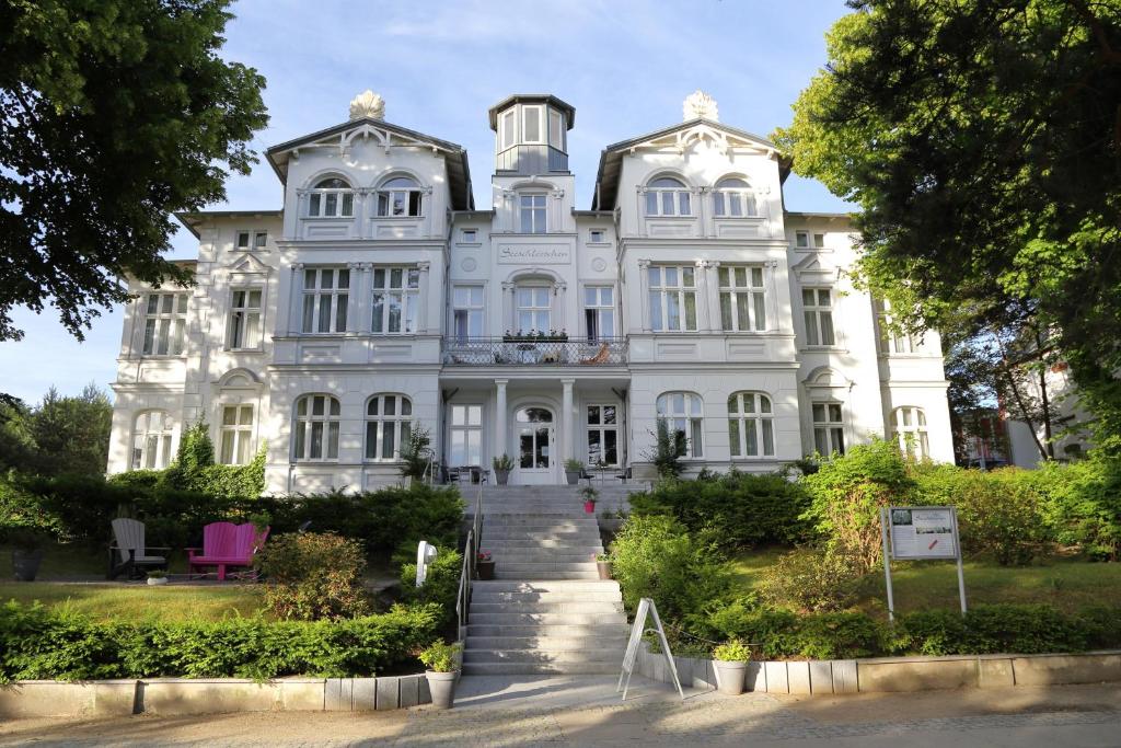 a large white house with a staircase in front of it at Aparthotel Seeschlösschen in Zinnowitz