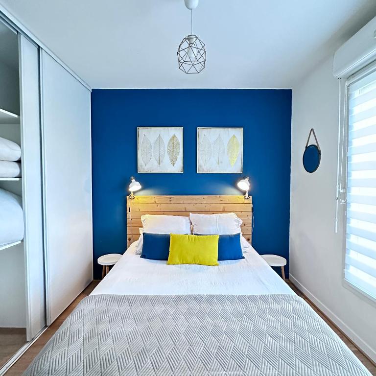 a bedroom with blue walls and a bed with yellow pillows at Beautiful apartment * parking* Disneyland 10 min in Montévrain
