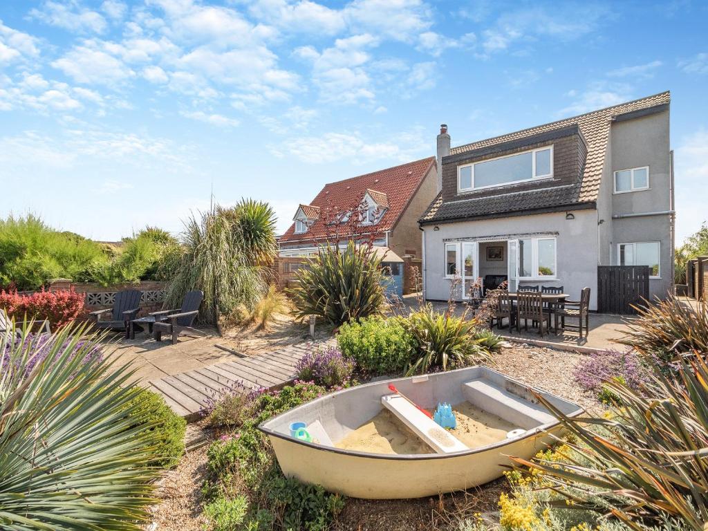 un giardino con una barca nel mezzo di una casa di Sea Star a Winterton-on-Sea