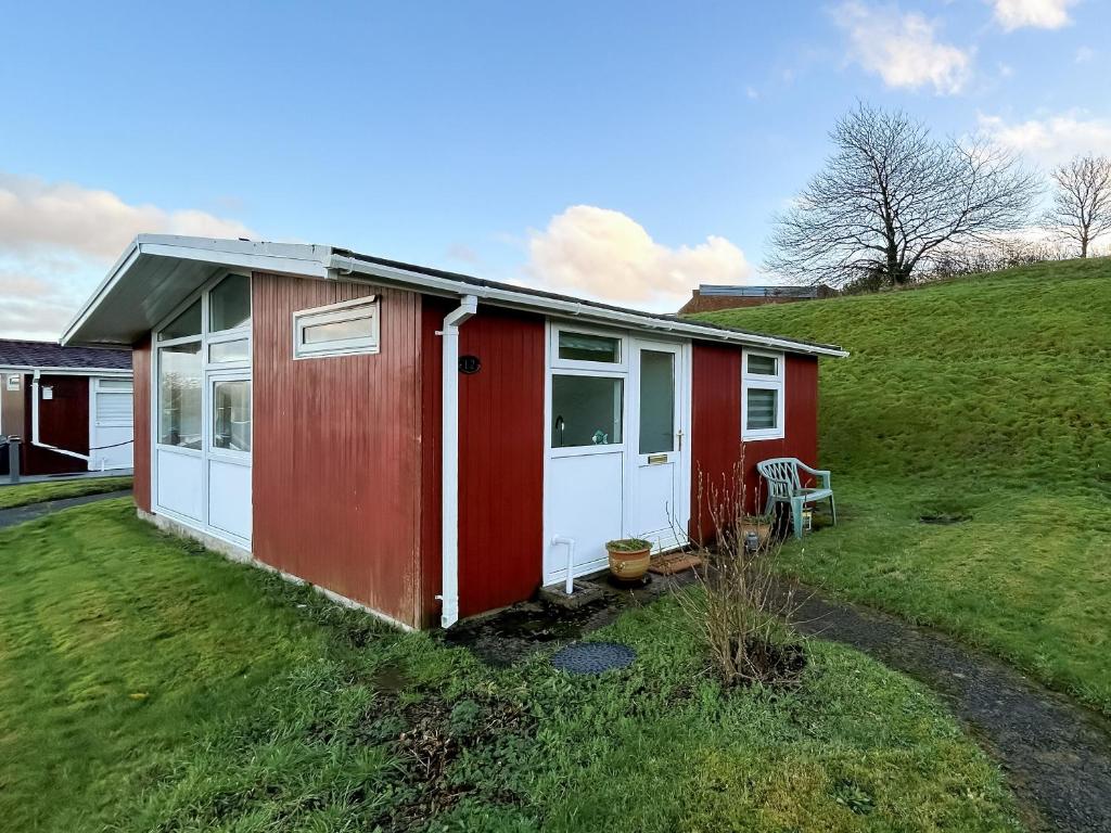 a red and white house on a grassy hill at Elmrise Park in Llangain