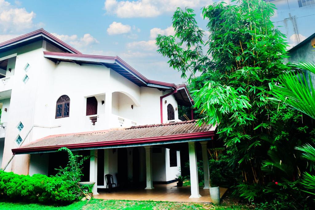 uma casa branca com uma árvore em frente em hikka T&O nature villa em Hikkaduwa