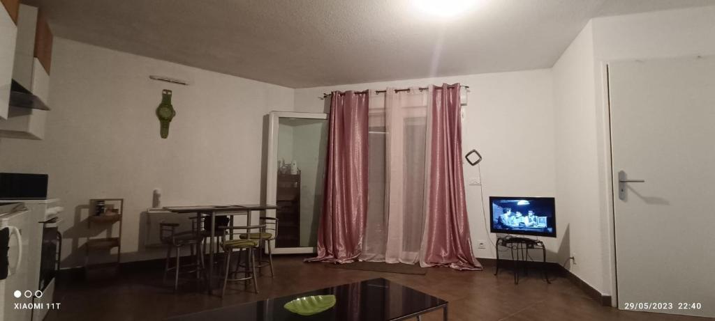 ein Wohnzimmer mit einem Esstisch und einem TV in der Unterkunft Appartement meublé in Montpellier