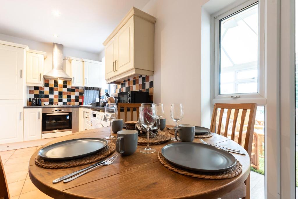 a kitchen with a wooden table with plates and wine glasses at Accessible 3-bedroom bungalow with patio +driveway in Southampton