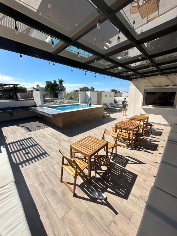 un patio con tavoli e sedie in legno accanto alla piscina di Las Frayadas, Departamento con Rooftop y Piscina, a 7 min de la playa de Nuevo Vallarta a Mezcales
