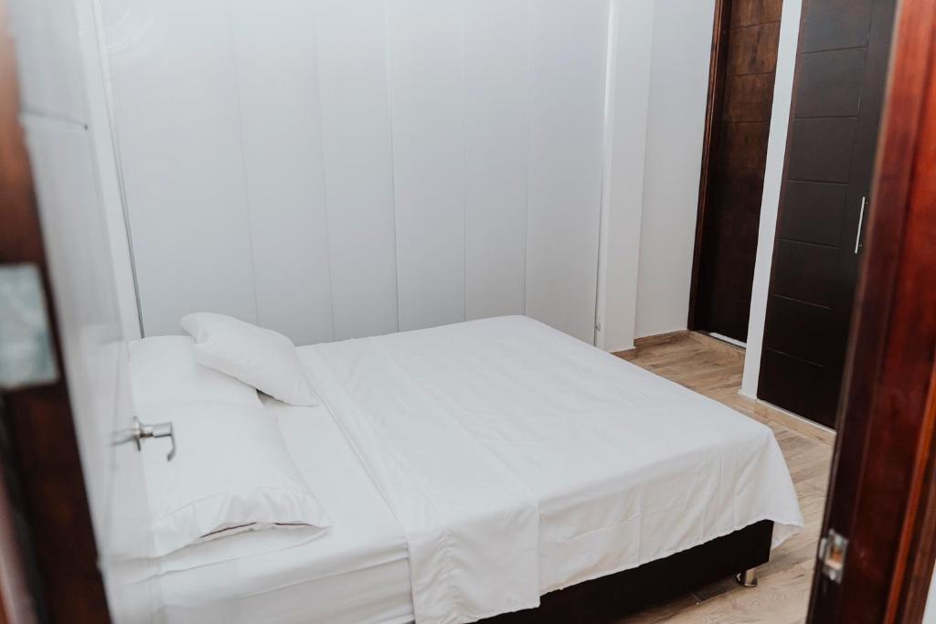 Cama blanca en habitación con espejo en Big Comfort Apartment en Valledupar
