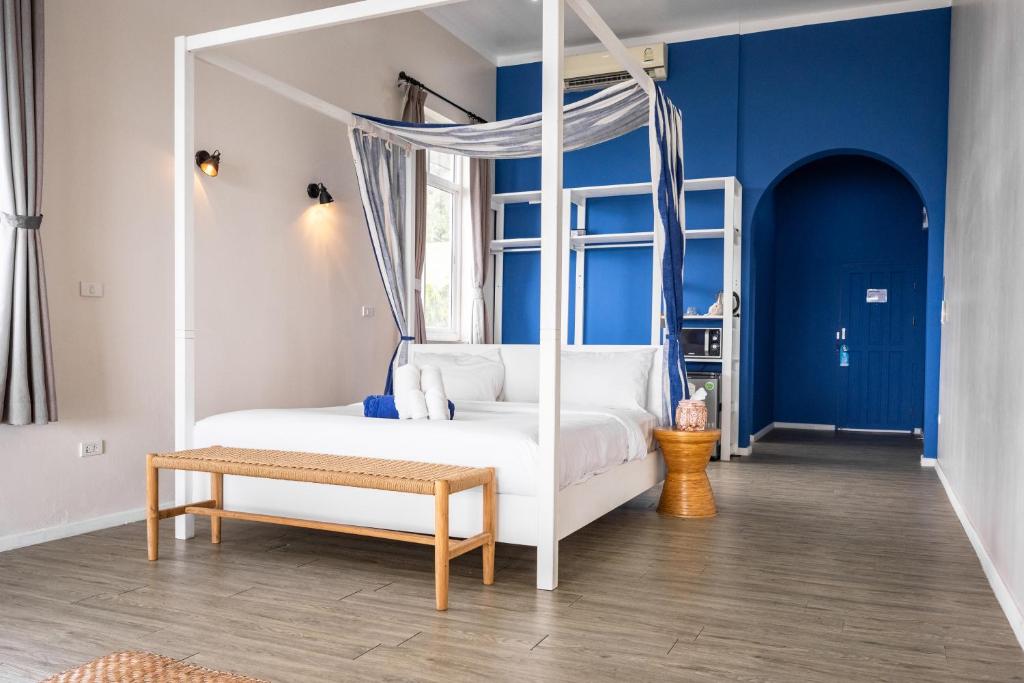 Baan Jai Dee Beach Front Hotel في ووك توم: غرفة نوم بسرير من المظلة البيضاء ومقعد