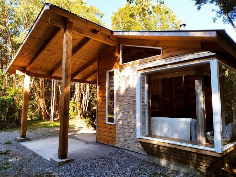 un pequeño edificio de ladrillo con una gran ventana y un techo en Arriendo Cabaña Entre Arrayanes., en Las Quemas del Salto