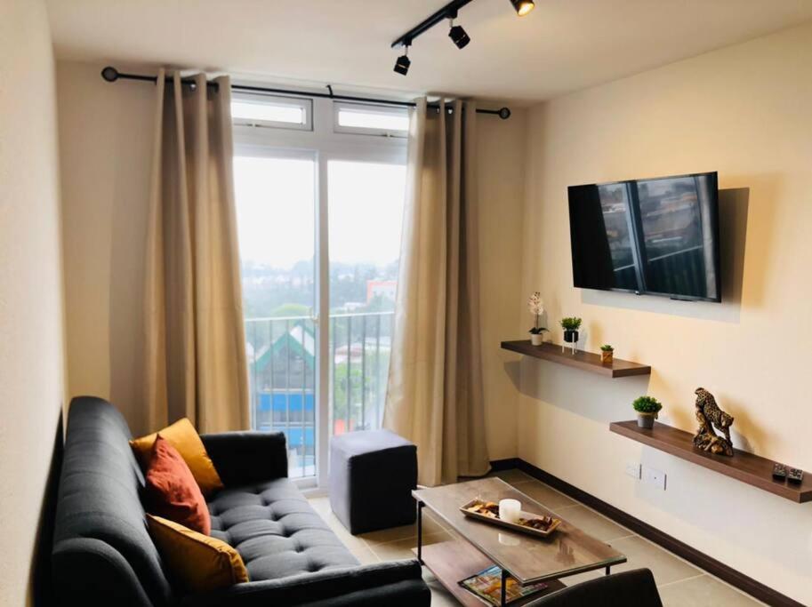 a living room with a couch and a large window at Exclusive Apartment, Calzada Roosevelt in Guatemala