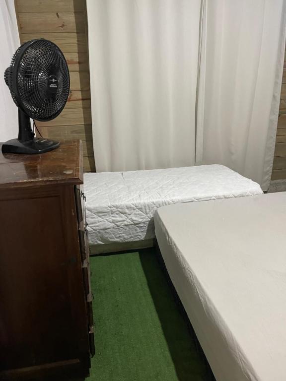 um quarto com 2 camas e uma secretária com uma ventoinha em KITNET cosntruçao quase já finalizada em Itapema