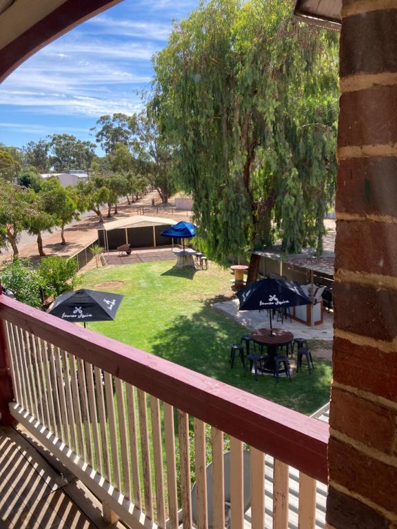 a balcony with a view of a yard with tables and umbrellas at Yealering Hotel in Yealering