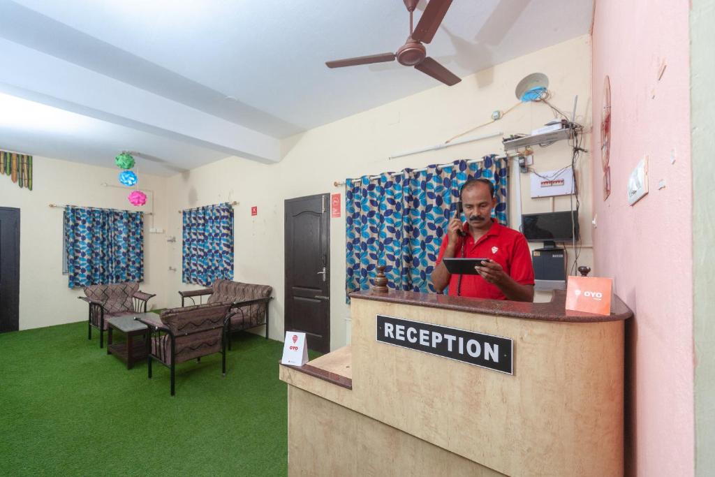 a man talking on a cell phone at a reception desk at OYO B Square Homes in Singānallūr